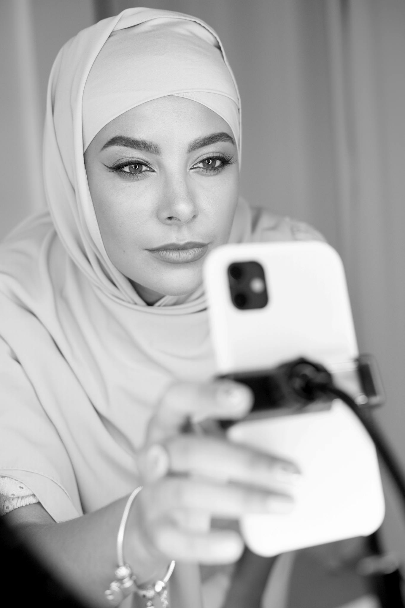 Muslim woman wearing hijab engaged in vlogging with a smartphone.